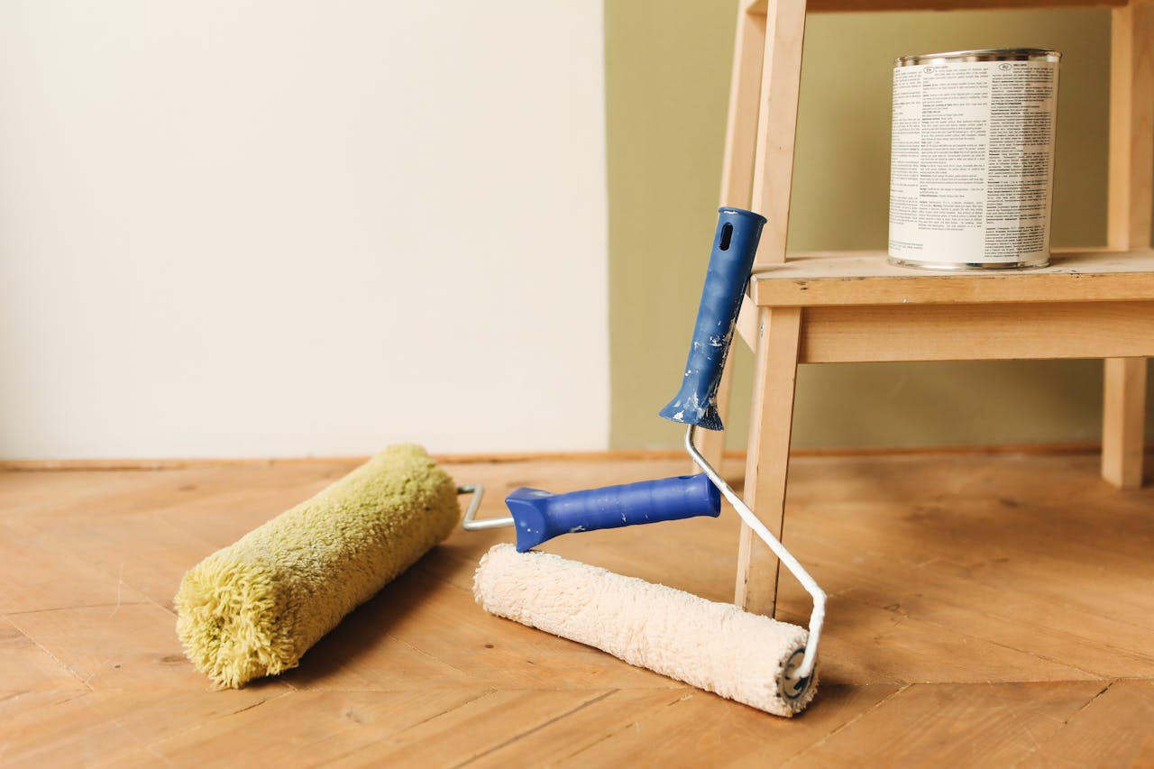 Paint rollers on wooden floor surface next to a can, ready for home renovation.